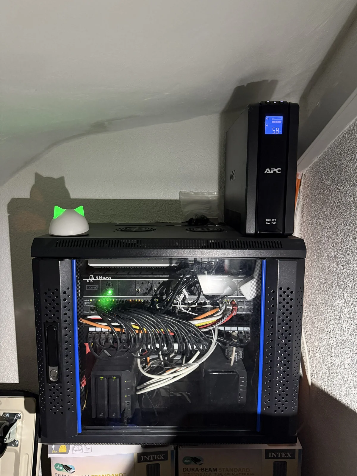 Netzwerkschrank im Homelab mit Switch, Patchkabeln und NAS, obendrauf eine USV