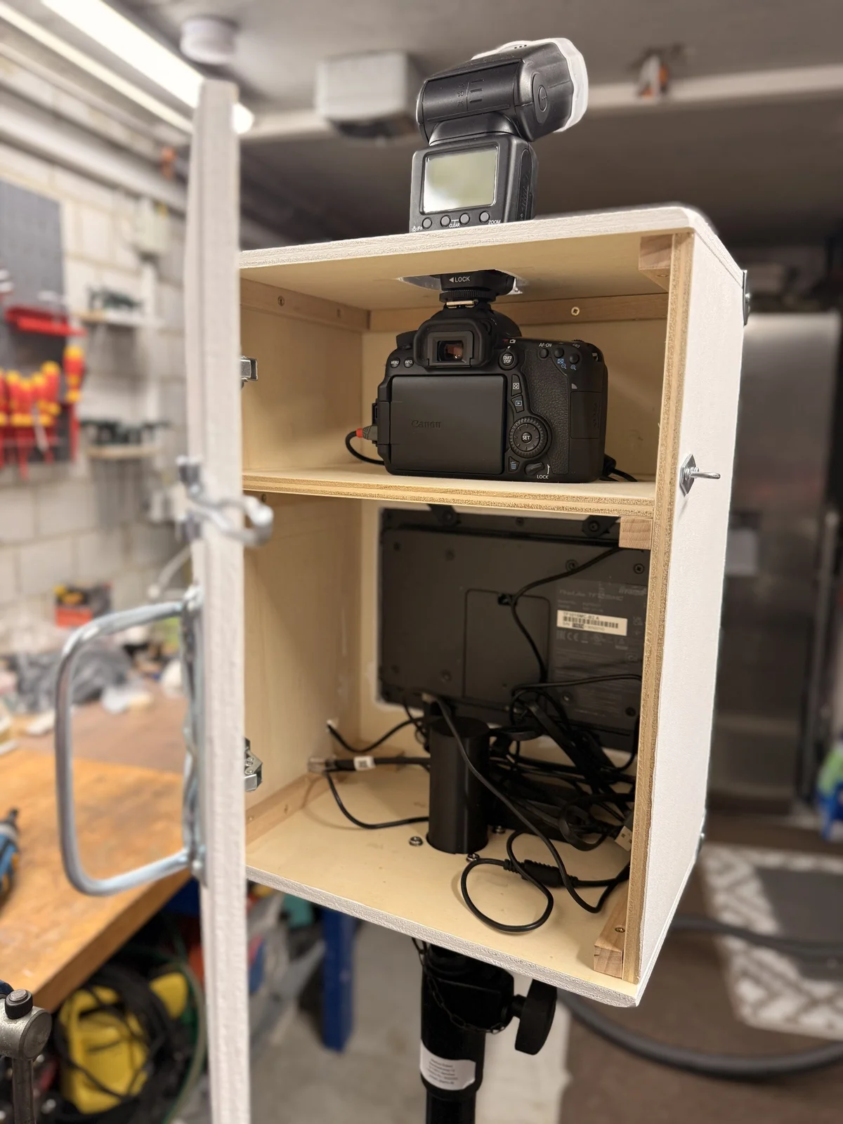 Geöffnete Fotobox in der Werkstatt: oben Kamera und Blitz, darunter der Bildschirm