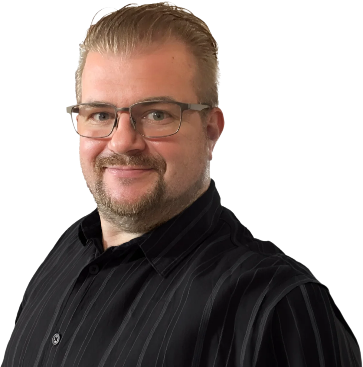Porträt von Markus Eckert: lächelnder Mann mit Brille und Kinnbart in dunklem Hemd