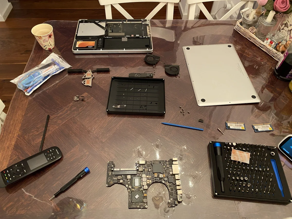 Zerlegtes MacBook Pro auf dem Esstisch: Gehäuse, Logicboard, Lüfter und ein Werkzeugset